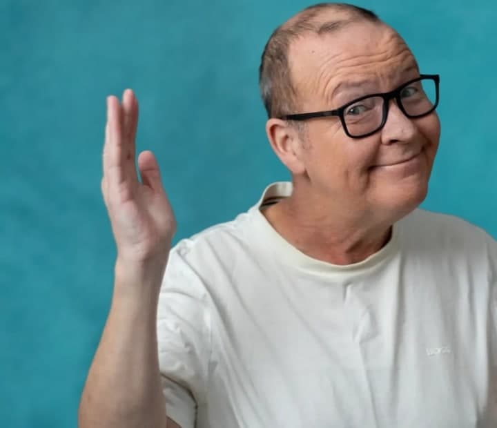 Paul Riley, comedian, waving at the camera