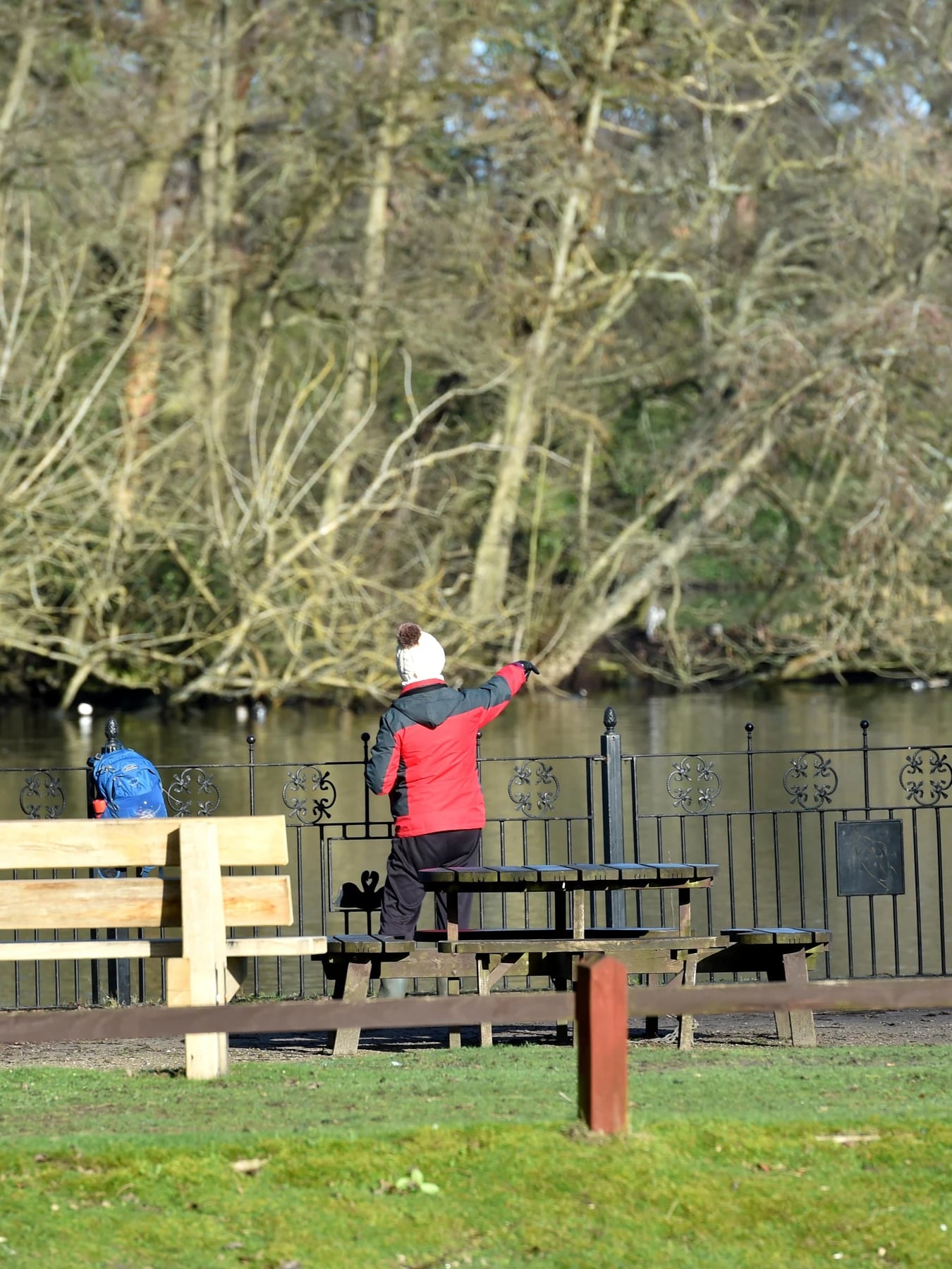 The backs of a young boy and an old man looking into a lake against railings.